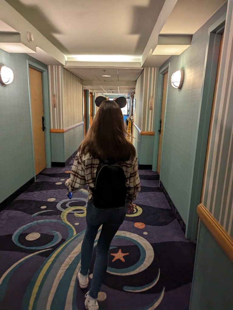 A girl wearing Mickey ears walks through the halls of Paradise Pier