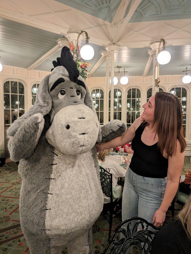 A woman smiles at Eeyore at The Crystal Palace Winnie the Pooh and friends character meal