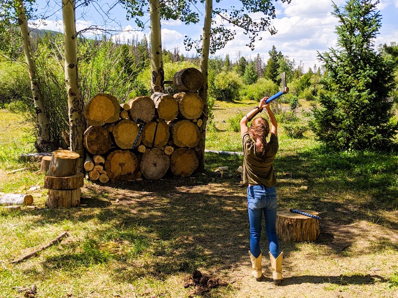 Girl throwing tomahawk at log wall.