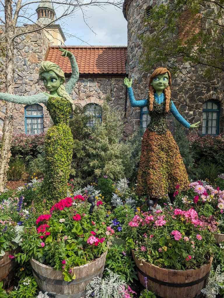 Elsa arms outstretched to make magic while Anna waves nearby at this Frozen inspired topiary