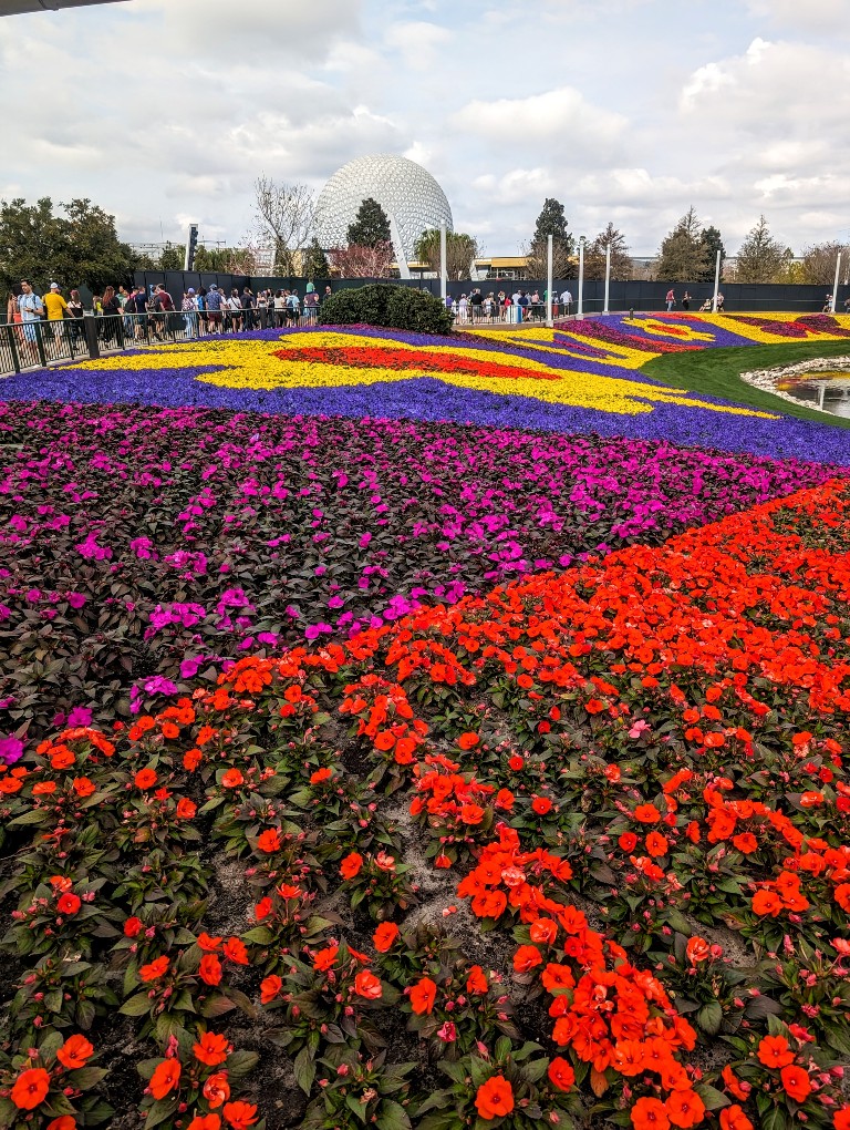 Hundreds of flowers in a variety of colors and patterns in front of Spaceship Earth