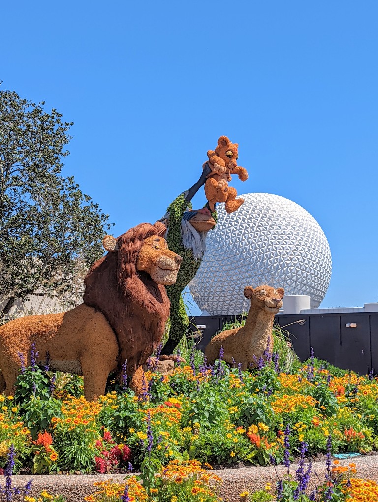 A striking topiary of Rafiki holds Simba high in front of Spaceship Earth during Epcot Flower and Garden Festival