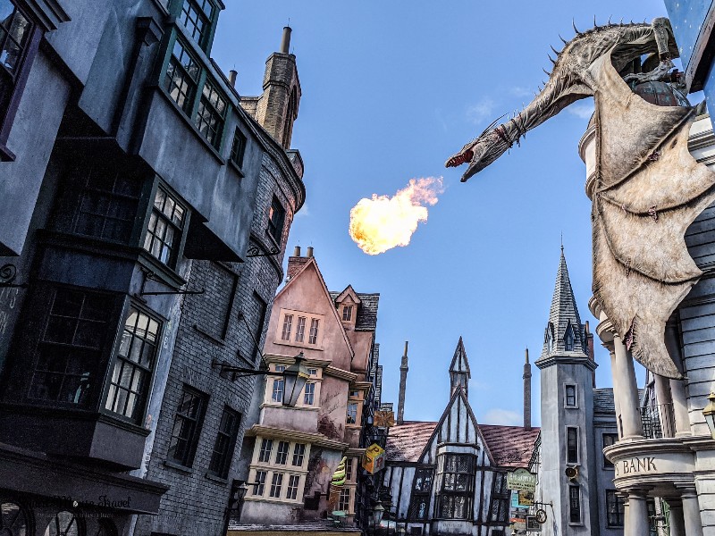 Dragon breathing fire over Diagon Alley. Although still magical, the Wizarding World of Harry Potter during COVID has several changes that you need to know when planning your trip.