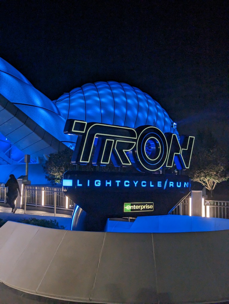 Tron Lightcycle Run sign and canopy in blue lights at night at Magic Kingdom