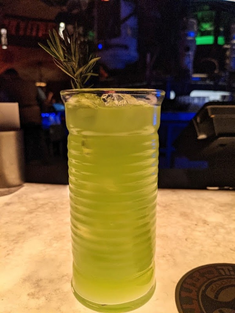 Bright green with a sprig of  rosemary garnish, the Dagobah Slug Slinger is a delicious Oga's Cantina drink