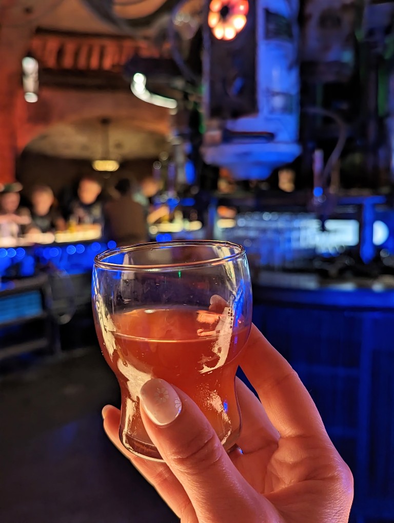 A tiny glass held aloft holds Jet Juice, a sweet but spicy cocktail at Oga's Cantina