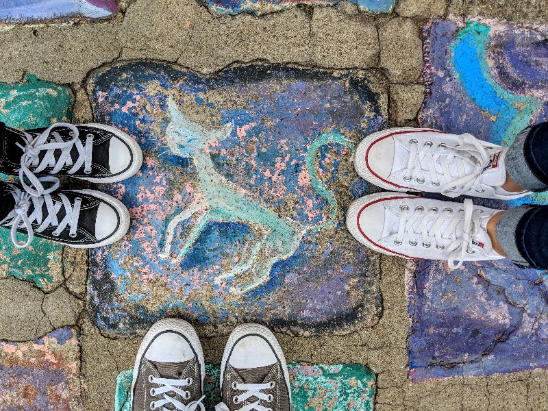 Three pairs of feet frame painted stone path when visiting Balboa Park with kids.