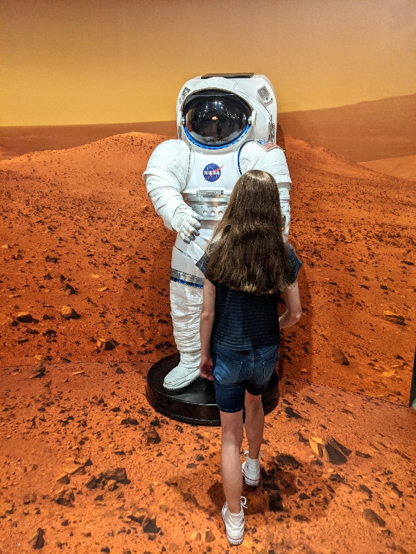 Girl approaches NASA astronaut suit at San Diego Air and Space Museum