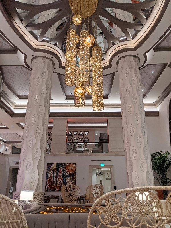 Ornate mirrored ceiling with delicate golden chandeliers and textured ivory columns off the Gran Destino Tower lobby