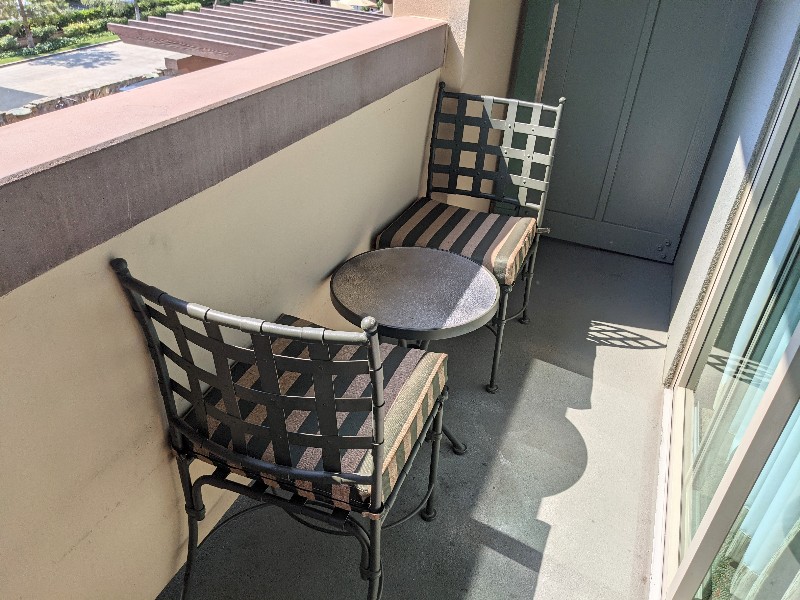 Two outdoor chairs plus a side table on a small balcony.