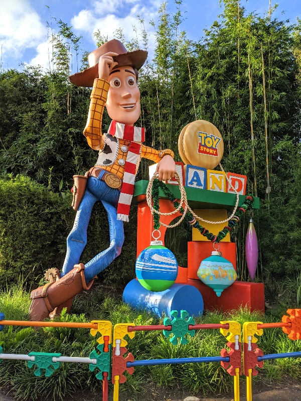 Woody in a striped scarf and ornaments hanging from the Toy Story Land sign during Disney World Christmas