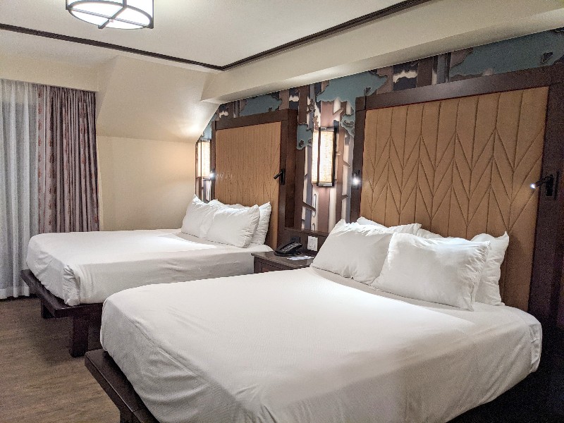 Two queen beds with stylized tree design behind the headboards.