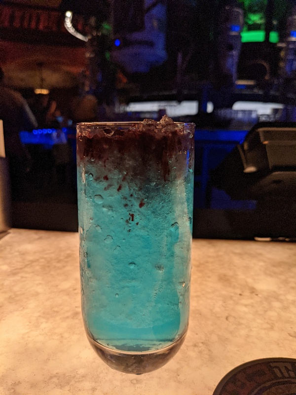 Hyperdrive, a non-alcoholic drink at Oga's, sitting on the lighted bar with bar decor in the background