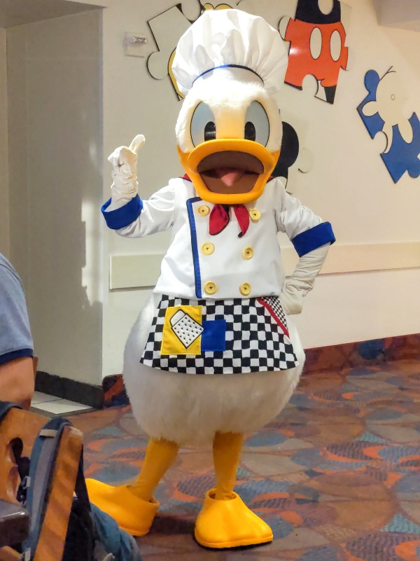 Donald Duck in a chef's coat, apron, and toque holds up his pointer finger reminding us that Donald Duck is #1