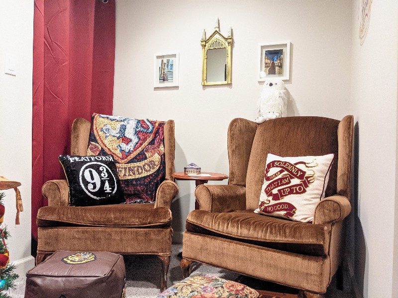 Two brown wingback chairs with Harry Potter throw pillows and blankets provide comfortable seating