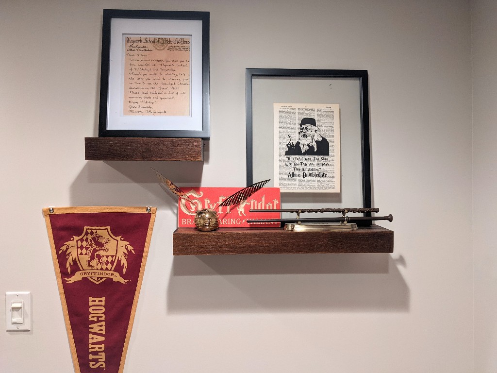 Shelves with a Hogwarts acceptance letter, pennant, and wands on a wand stand in our DIY Gryffindor common room