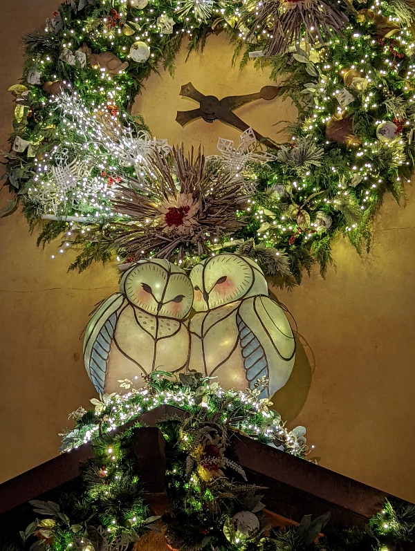 A wreath adorned with natural elements hung above two snuggling owl luminaries make for stunning Animal Kingdom holiday decorations