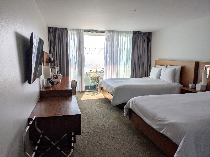 Two queen beds with white linens and light wood headboards in a spacious room