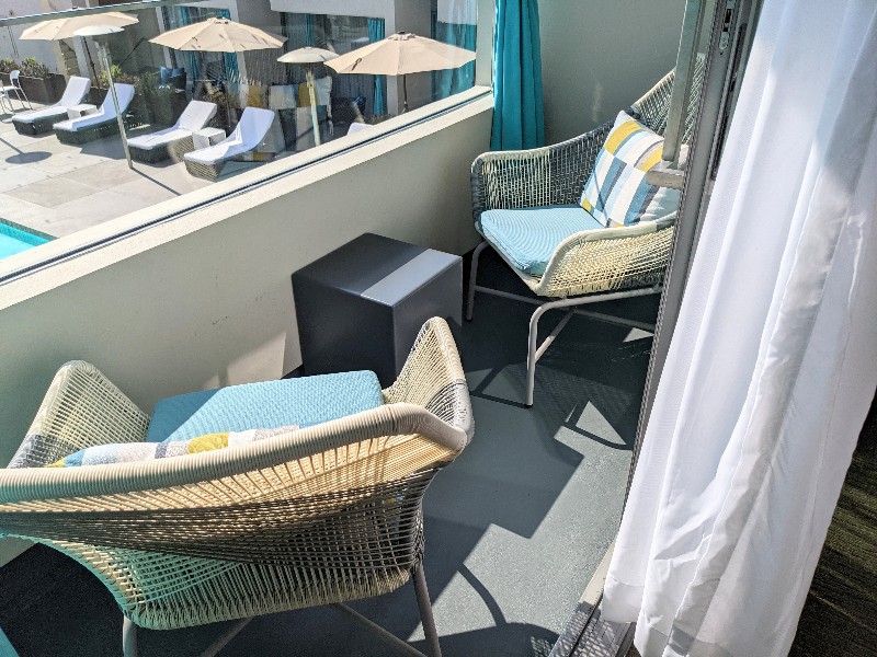 Two woven chairs with bright teal cushions are a comfortable spot to relax and watch the ocean.