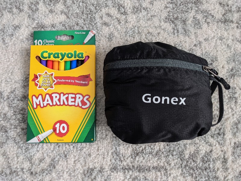 Gonex Ultralight backpack folded up next to a box of markers as a size comparison