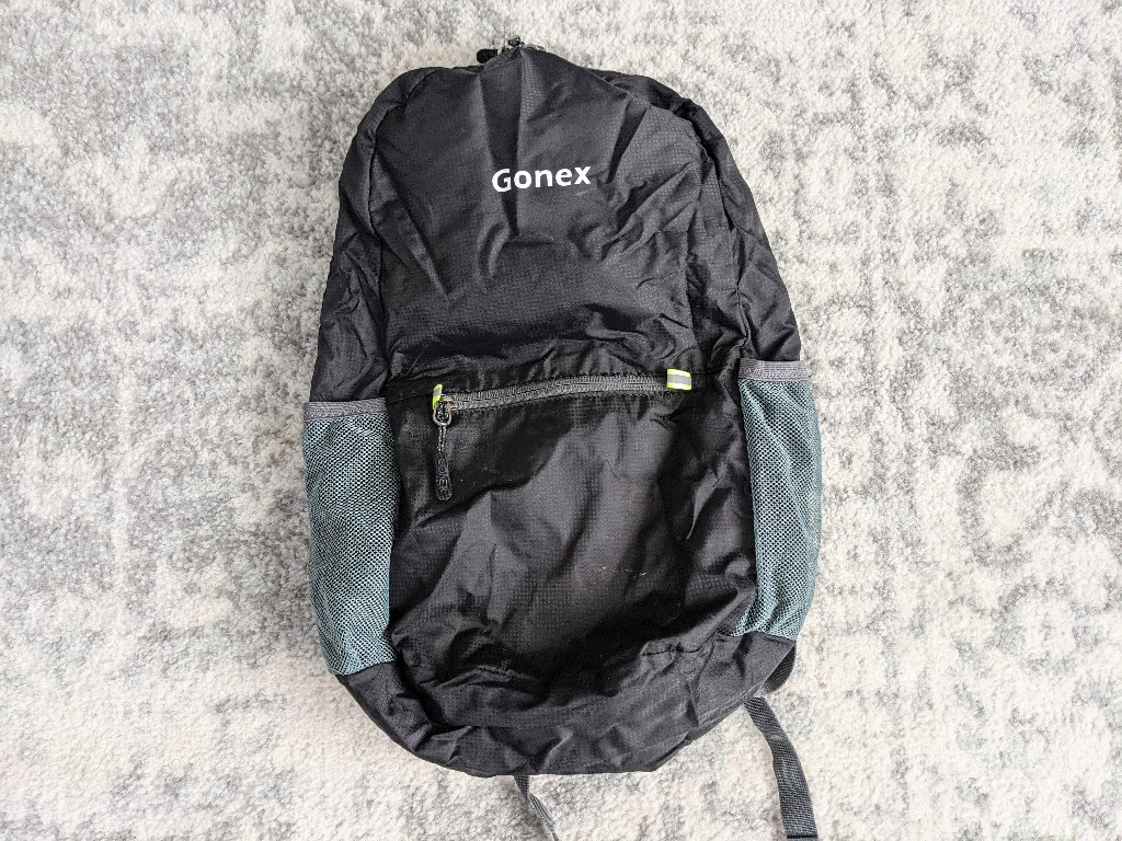 Unfolded backpack showing logo and front zipper pocket