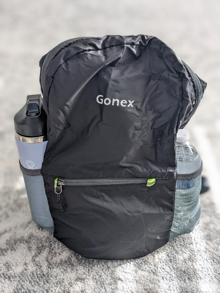 Gonex Ultralight backpack holding a 20 ounce Hydroflask in one side pocket and 16 ounce disposable water bottle in the other