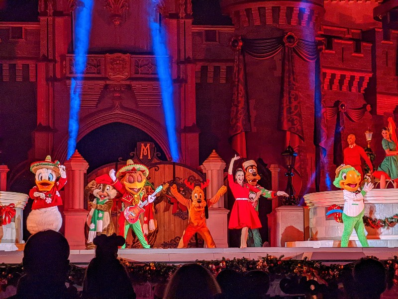 The Three Caballeros and other Disney characters perform Christmas songs in front of Cinderella Castle