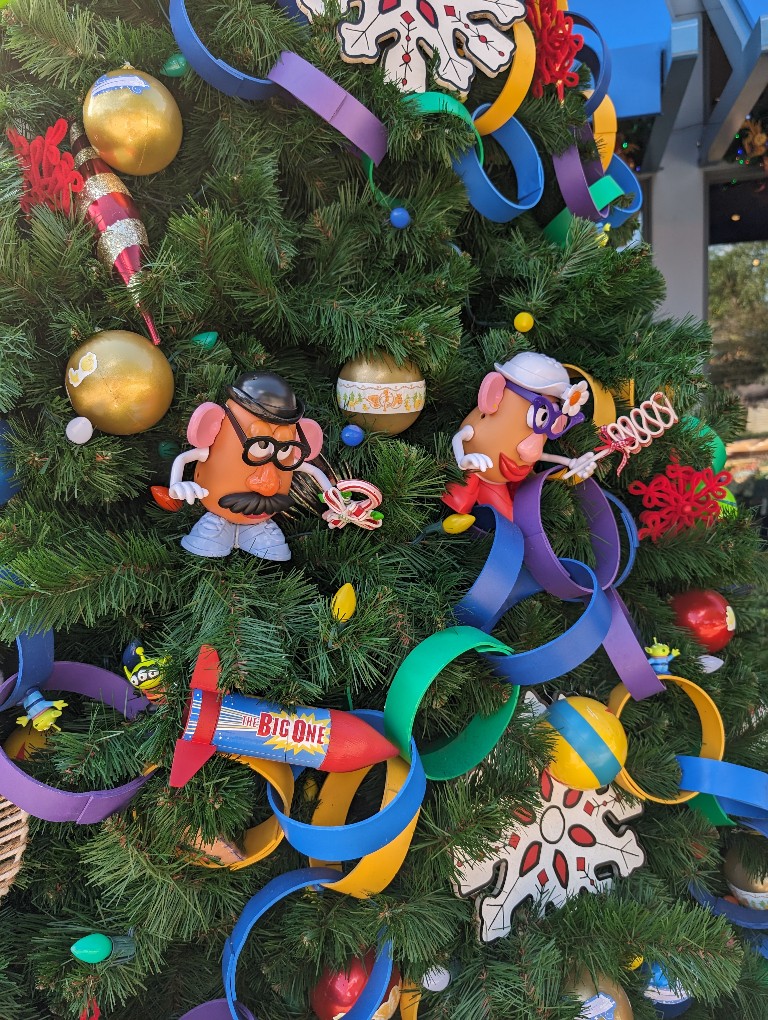 Mr and Mrs Potato Head peek out from the branches of a Toy Story themed Christmas tree on the Disney Springs Christmas Tree Stroll