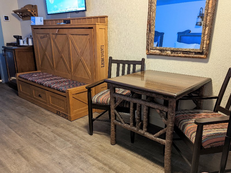 A bench converts to a twin bed next to a table with two rustic chairs