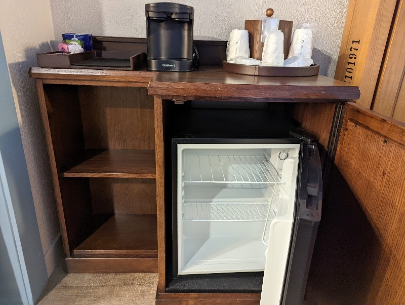 A mini fridge hidden in a cabinet underneath a coffee maker and supplies at Port Orleans Riverside