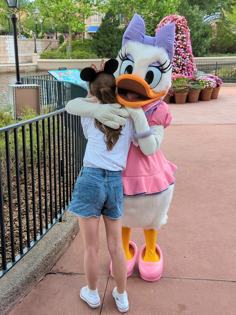 A girl hugs Daisy Duck at Epcot's International Gateway