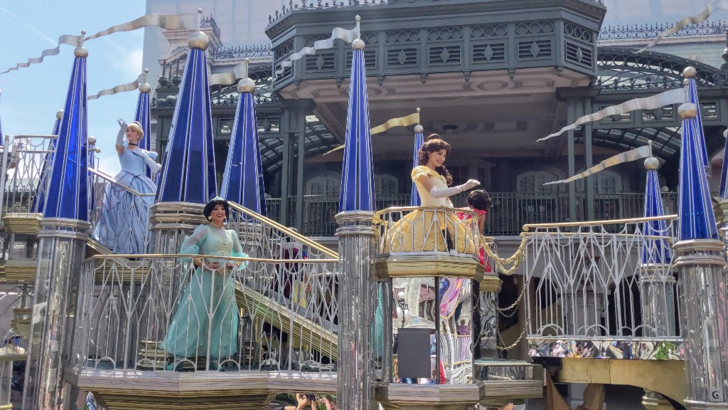 Belle, Jasmine, and Cinderella wave to Disney World guests during a Magic Kingdom cavalcade