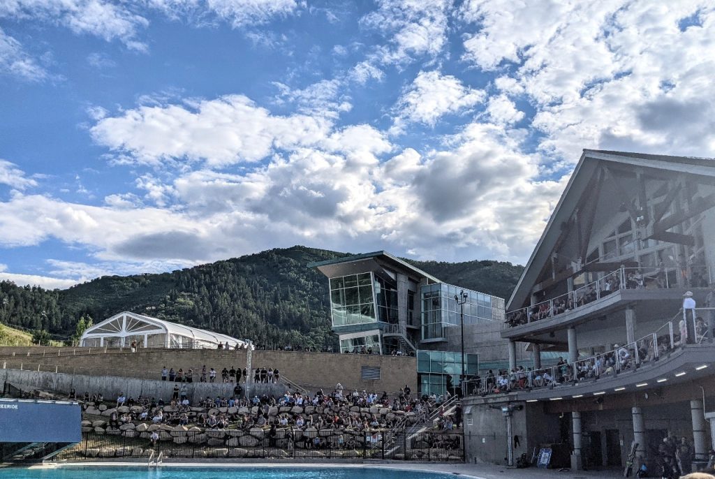 Mountains framed by a blue sky showcase the open seating area around the Utah Olympic Park pool