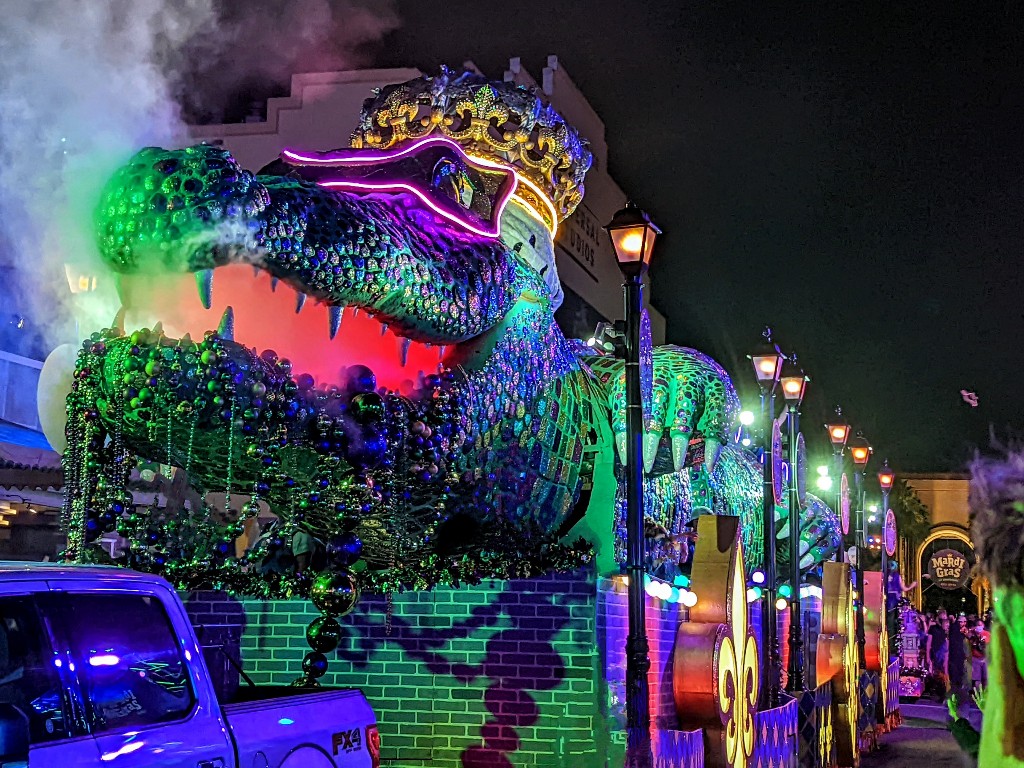 A smoke breathing alligator float draped in beads and glitter closes the Universal Mardi Gras parade