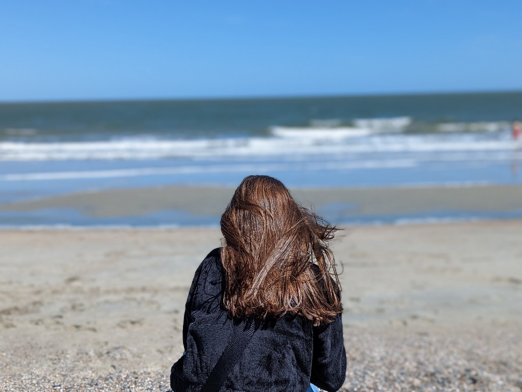Wind blows a girls hair as she looks for shells on Tybee Island