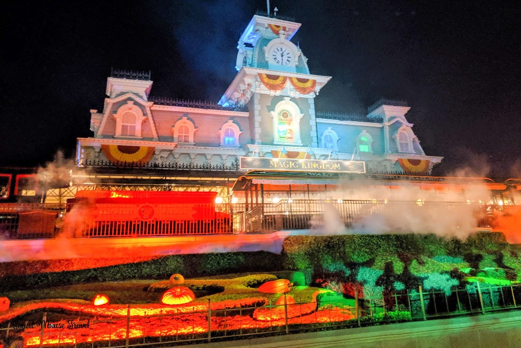 Magic Kingdom's Main Street train station looks spooky with orange and green lights plus fog