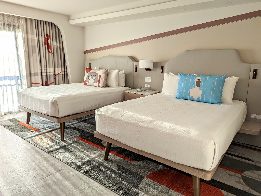 Two queen beds with Edna Mode and Frozone pillows greet you in a Contemporary Main Tower room