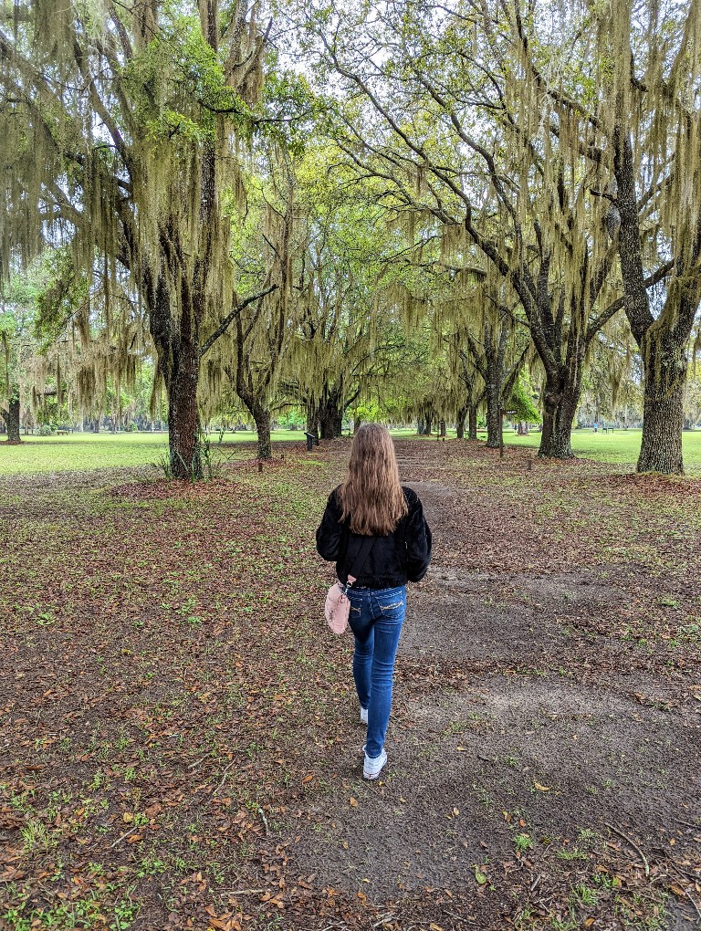 A girl walks through moss draped trees at Fort Frederica