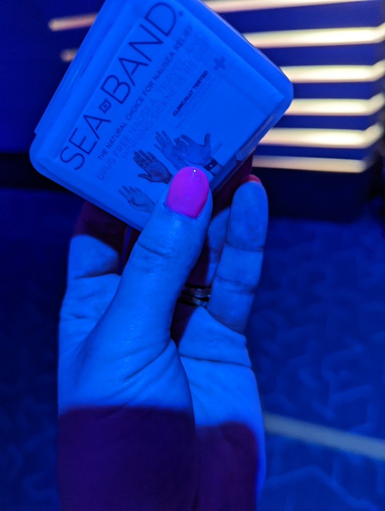 A woman holds Sea Bands inside Guardians of the Galaxy: Cosmic Rewind to prepare for motion sickness issues