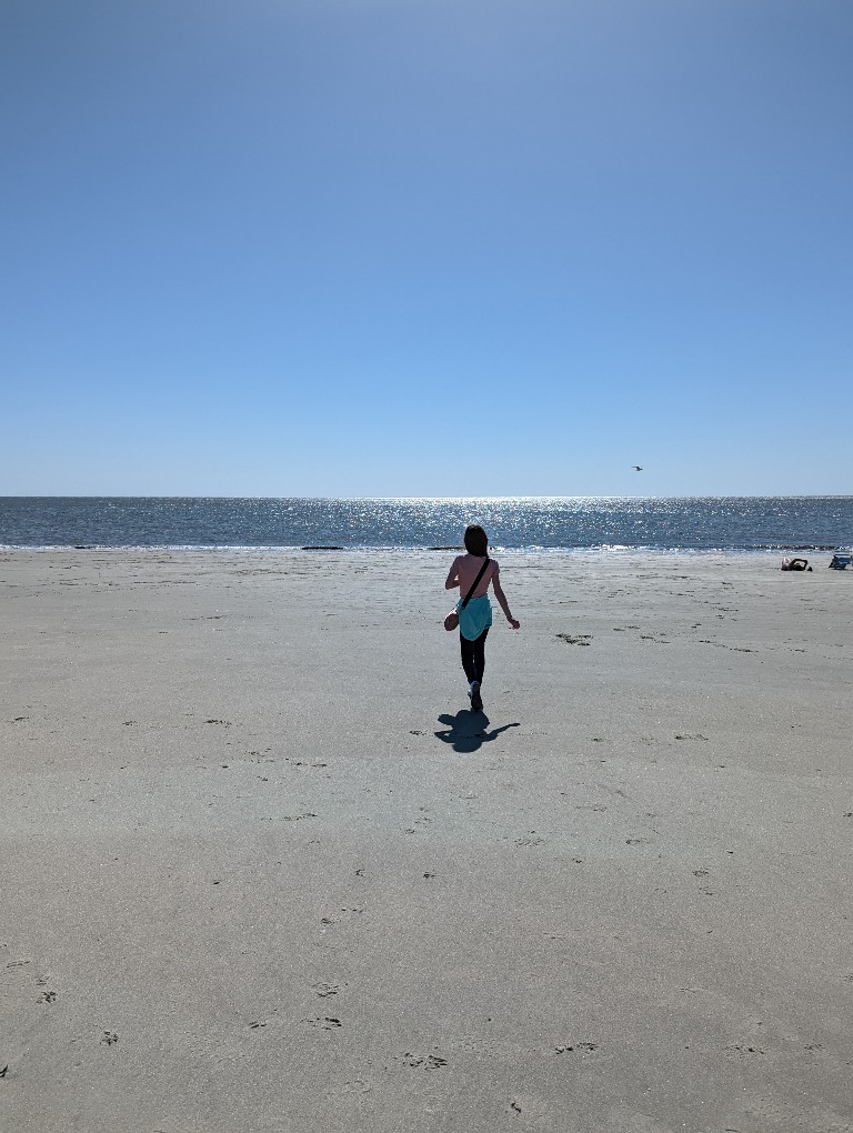 A girl walks along the beach comparing Georgia islands