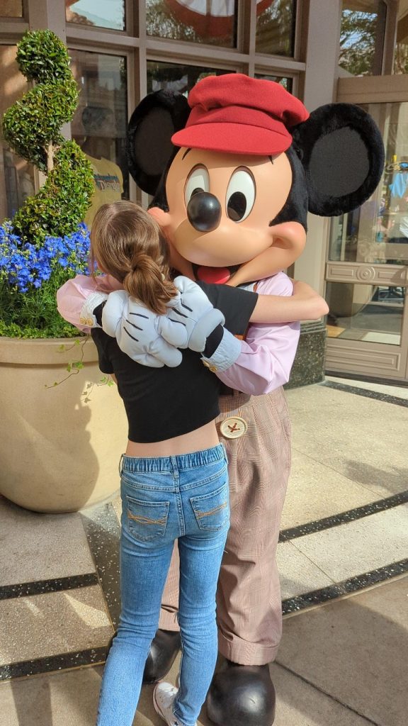 Mickey hugs a girl at Disneyland before signing an autograph
