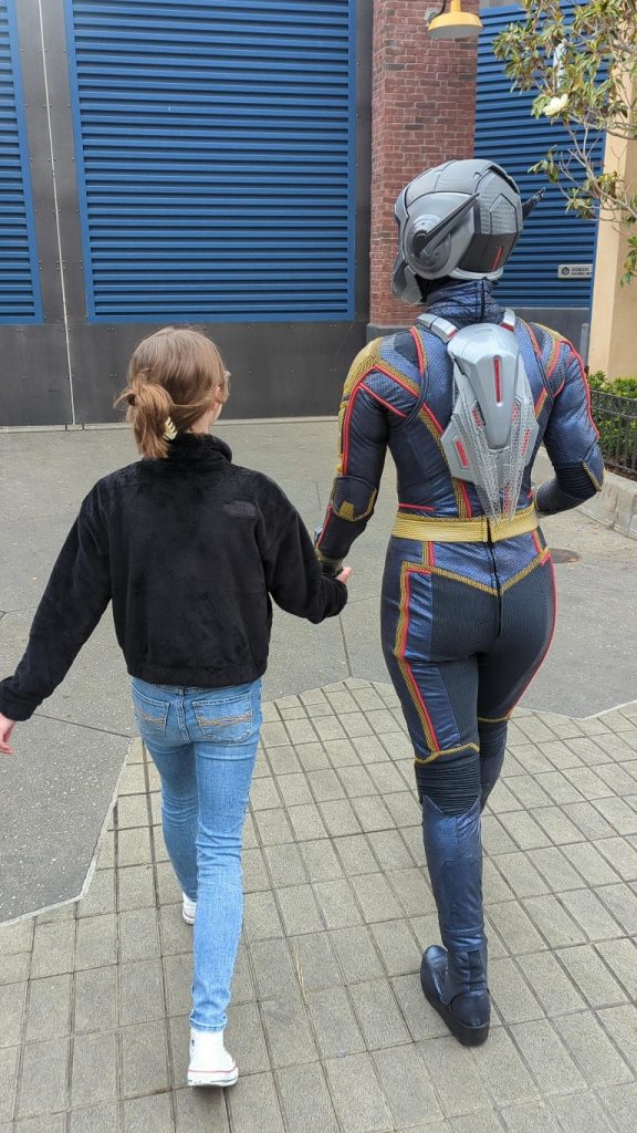 A girl walks with The Wasp at Avengers Campus after finding Disneyland characters