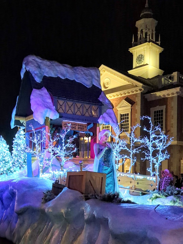 Elsa stands on a float of snow and sparkling icicles during a parade at Mickey's Very Merry Christmas Party 