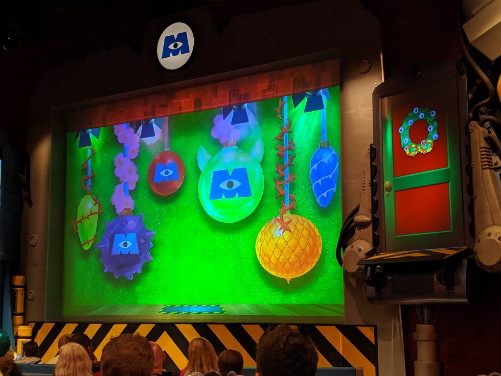 Ornaments decorate the screen before the Monsters Inc Very Merry Christmas Party Overlay show begins