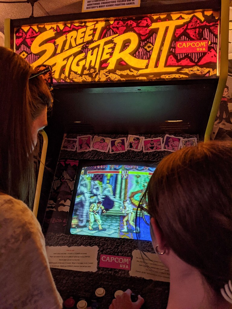 A woman and girl square off playing Street Fighter at Asheville Pinball Museum