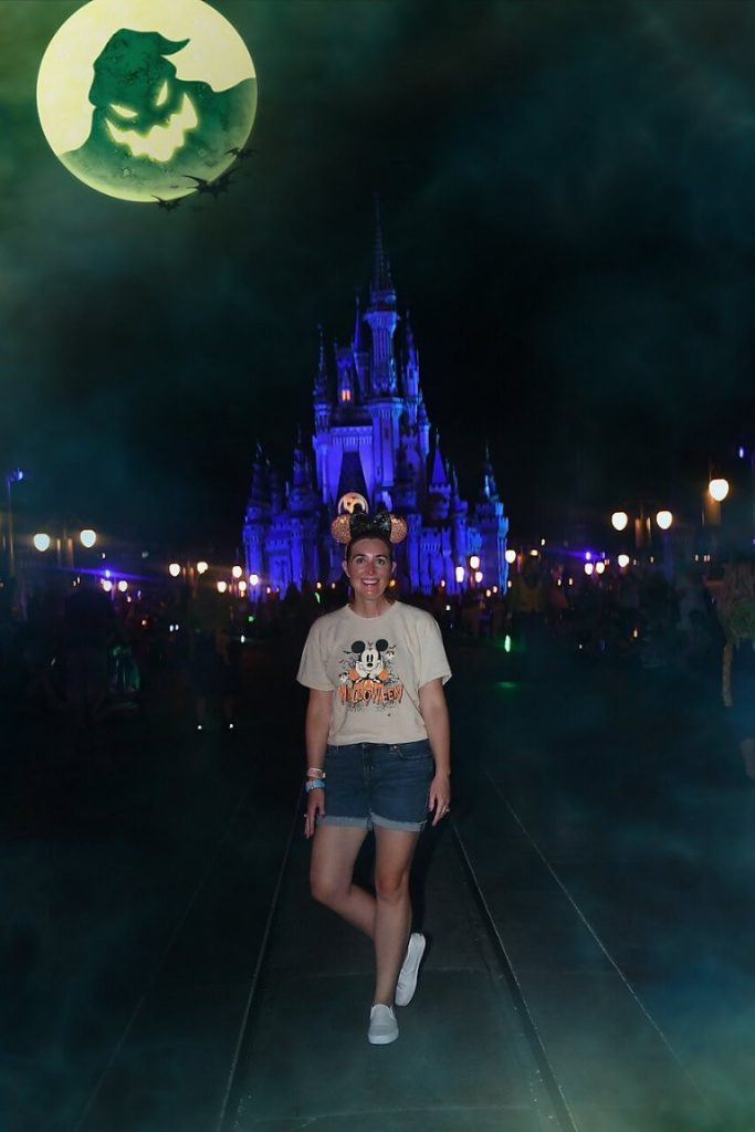 Oogie Boogie's shadow looks down over Cinderella Castle and a woman posing on Main Street at MNSSHP