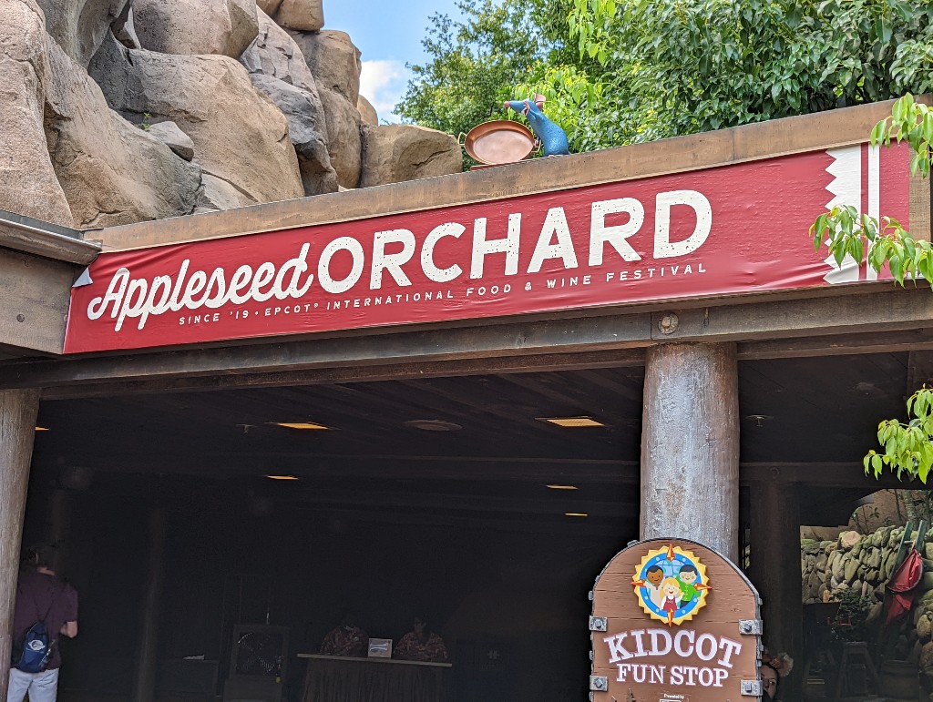 Remy peeks over the Appleseed Orchard sign near Kidcot