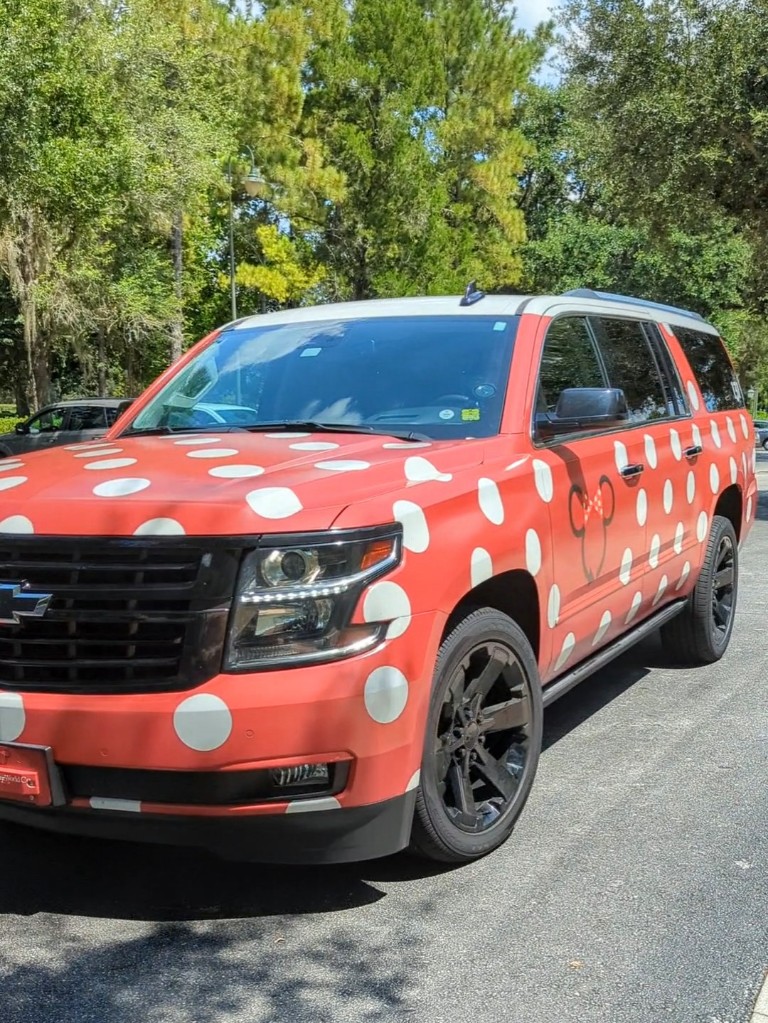 A Minnie Van pulls up in front of a Disney World resort