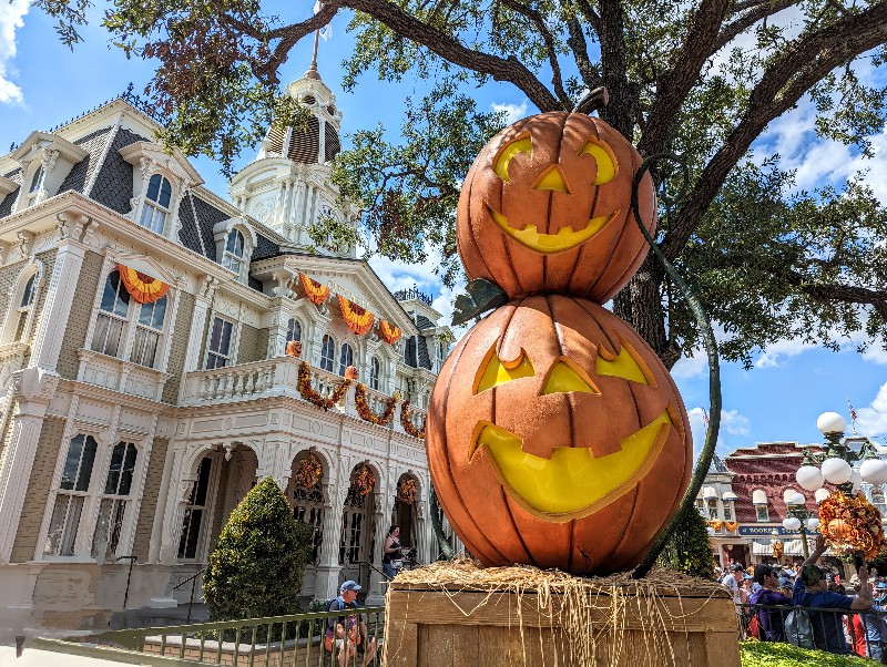 Stacked jack-o-lanterns in the foreground with Town Hall decorated in fall bunting