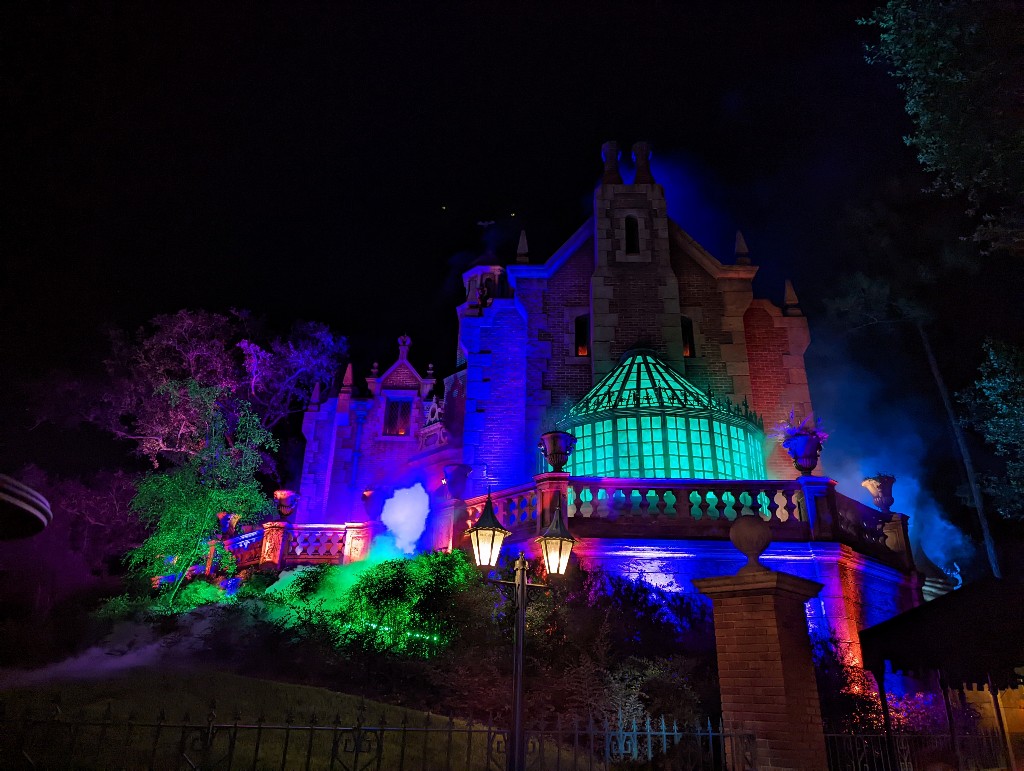 Haunted Mansion lit in spooky purple, green, and red during Mickey's Not So Scary Halloween Party